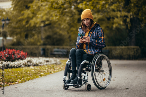 Woman in wheelchair using a smartphone while out in the city park