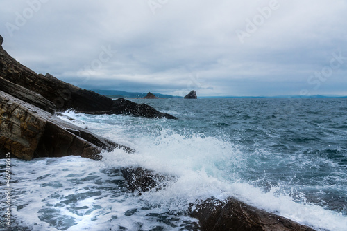 Sea and rocks with the horizon in the background. Cloudy and rainy with quite a lot of waves