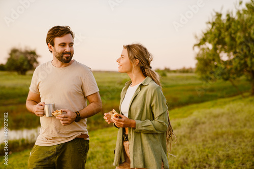 White couple talking and eating sandwiches while hiking together