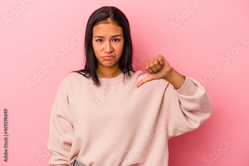 Young latin woman isolated on pink background showing thumb down, disappointment concept.