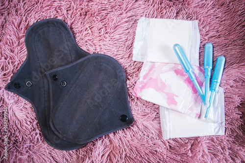 Dos compresas menstruales de algodón reutilizables junto a los tradicionales tampones y compresas sobre un fondo rosa. Concepto de períodos cero residuos