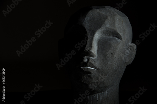 portret kamiennej głowy na czarnym tle, twarz częściowo oświetlona