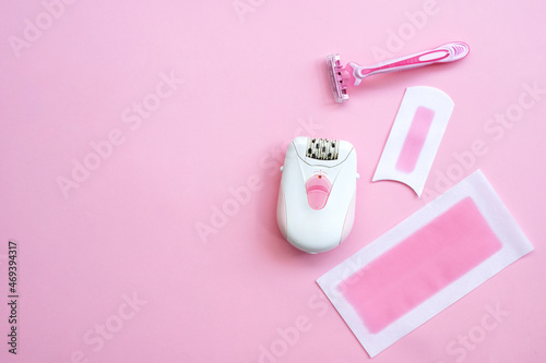 Pink epilator with wax strips and razor for removal of unwanted hair. Flat lay
