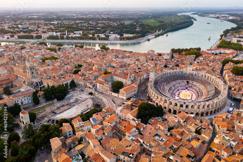 Cityscape of Arles, southern France. Tiled roofs of buildings, Arles Amphitheatre and Rhone River visible from above.