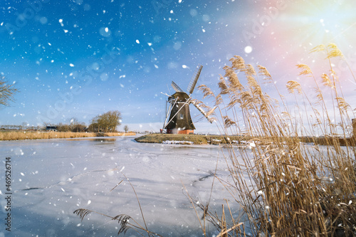 Typical winter dutch landscape with windmill. frozen canal in netherlands. Traditional winter holland scene. winter snow covering windmills and water.