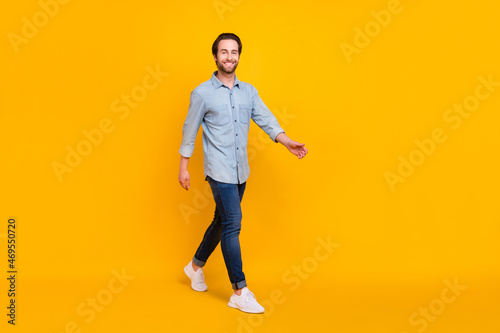 Full body profile side photo of young handsome man happy positive smile go walk step isolated over yellow color background