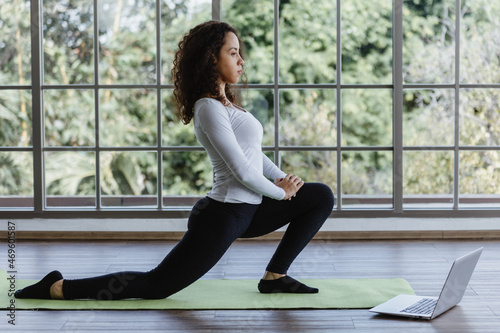 Young woman doing front lunges or squat exercise at home