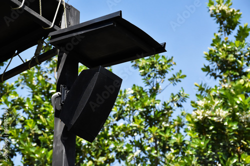 Mini speaker of the outdoor stage installed on the black metal pole which has metal roof above to protect it from the rain.