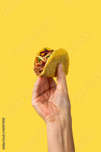 Hand holding a Mexican taco beef on yellow background