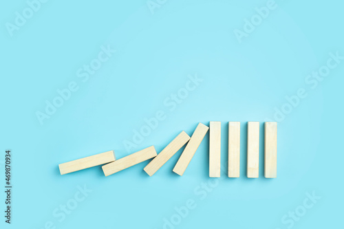 Falling pieces of dominoes on a clean blue minimal background. Business, risk, management and finance concept.