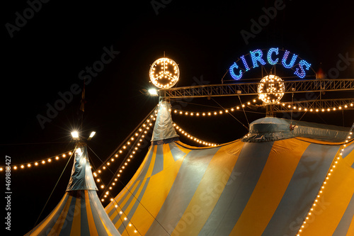 A circus tent at night with its colorful lights on 