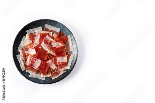 Spanish serrano ham slice on black plate isolated on white background