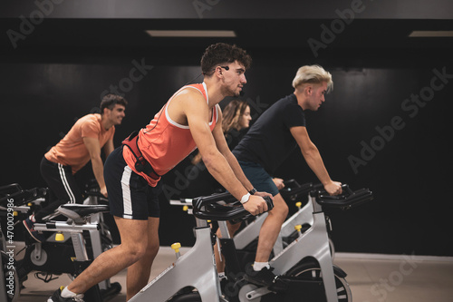 4 young people giving an exercise bike class in a gym.