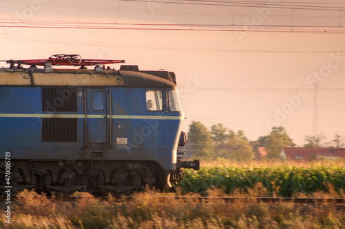 Polska elektryczna lokomotywa towarowa jadąca wczesnym wieczorem w stronę zachodzącego Słońca.