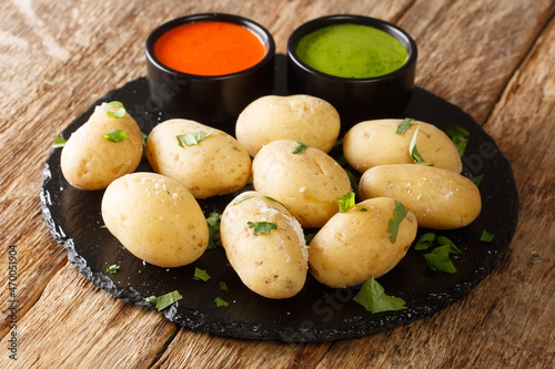 Wrinkled Potatoes with Red and Green Sauces close up in the plate on the table. Horizontal