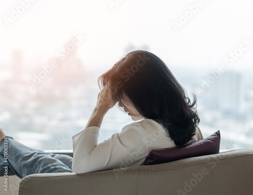 Anxiety disorder menopause woman, stressful depressed, panic attack person with mental health illness, headache and migraine sitting with back against wall on the floor in domestic home