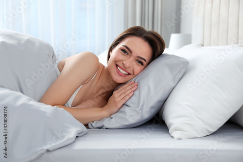 Young woman lying in comfortable bed with silky linens