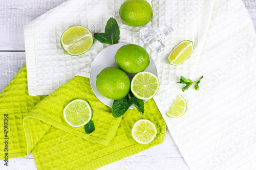 Top view of fresh green juicy limes and lime slices with mint leaves in the kitchen on light background.