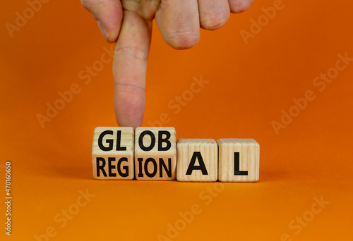 Regional or global symbol. Businessman turns wooden cubes and changes the word 'regional' to 'global'. Beautiful orange table, orange background. Business and regional or global concept. Copy space.
