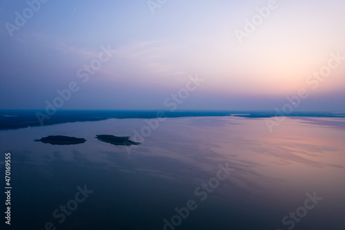Moody sunset over the lake. Two islands in the middle of the water. Pastel colors. 