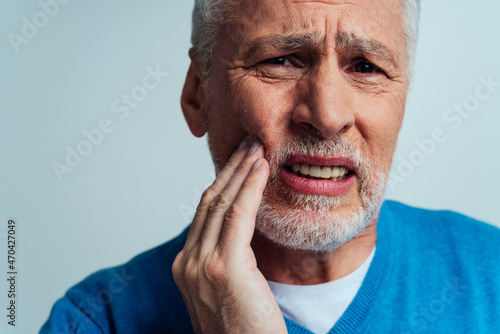 Handsome senior isolated on grey background. Old man feeling pain. Concept about the third age and seniority