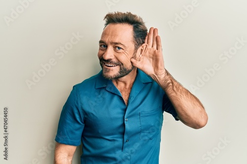 Middle age man wearing casual clothes smiling with hand over ear listening and hearing to rumor or gossip. deafness concept.