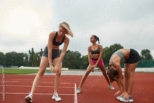 Group of women stretching on stadium treadmill