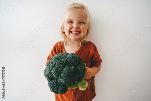 Child with broccoli vegetable healthy food vegan cooking eating sustainable lifestyle organic veggies harvest plant based diet nutrition funny kid girl happy smiling toddler