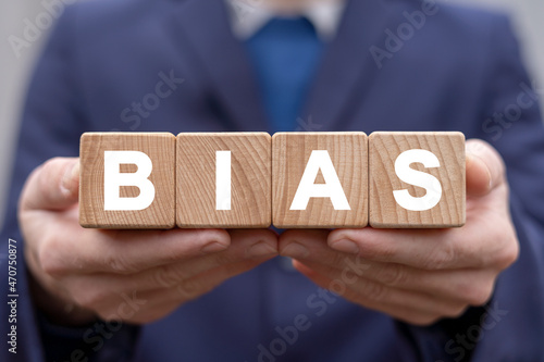 Concept of bias. People biases and facts. Prejudice, Bias, Discrimination, Ethics, Human Rights, Diversity. Businessman holding four wooden alphabet blocks with bias word.