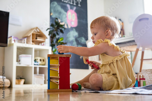 Happy girl toddler hitting wooden hammer on colored balls early development ecological toy