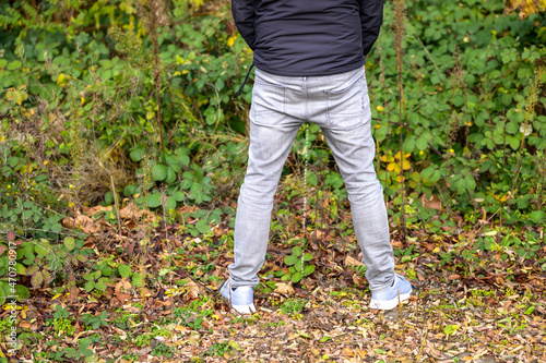 Rear view of a man urinating outdoors in a park