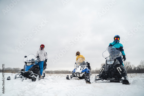 Snowmobile riders in snowy terrain, sportswear, cross helmet