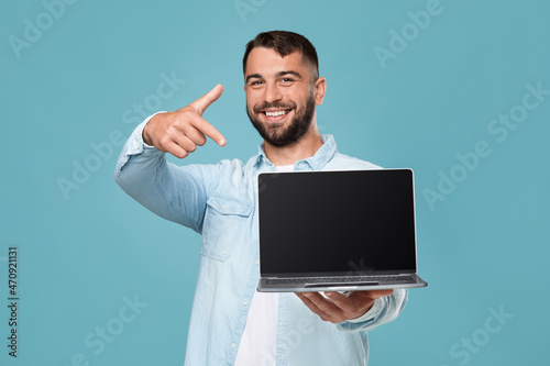Happy mature attractive european guy show finger at laptop with blank screen