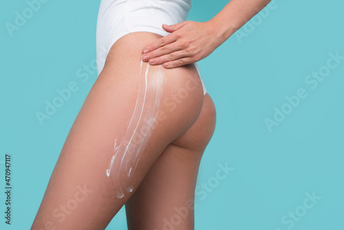 Slim womans legs. Cosmetic cream on woman buttocks with clean soft skin. Applying moisturizer cream on ass. Cellulite or anti cellulite treatment. Body care and spa salon concept.