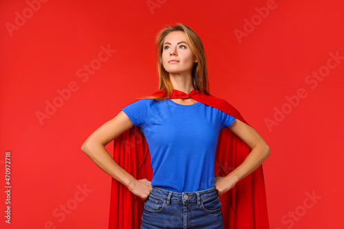 Confident woman wearing superhero cape on red background