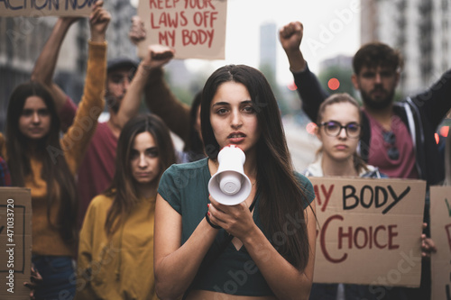 Generation z group of young people march in protest to affirm the right to abortion - protesters raise placards praising women's rights