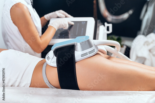 Woman lying receiving epilation laser treatment and anticellulite massage on buttock on the spa center.