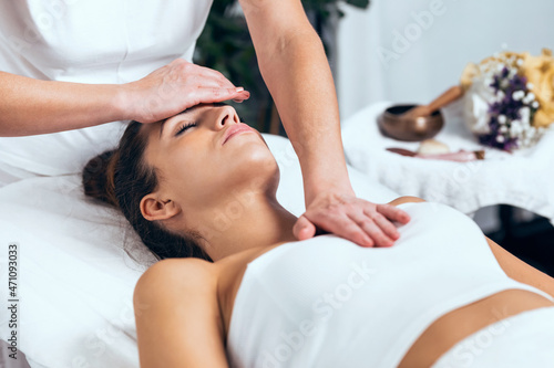 Beautiful young woman having reiki healing treatment in health spa center