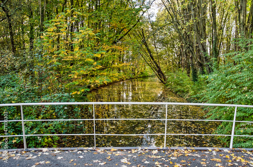 View from a pedestrian bridge across a narrow canal in Zuiderpark in Rotterdam, The Netherlands in autumn