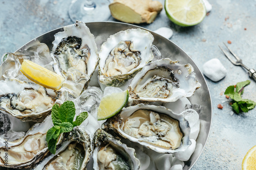 Fresh oysters with lime on a round plate. seafood dish. Oyster on the half shell. Restaurant menu, dieting, cookbook recipe