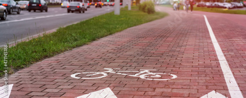 Bike sign painting with white dye on tiled sidewalk near city road