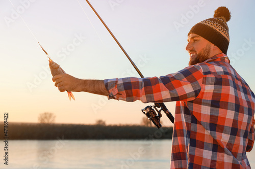 Fisherman with rod and caught fish at riverside