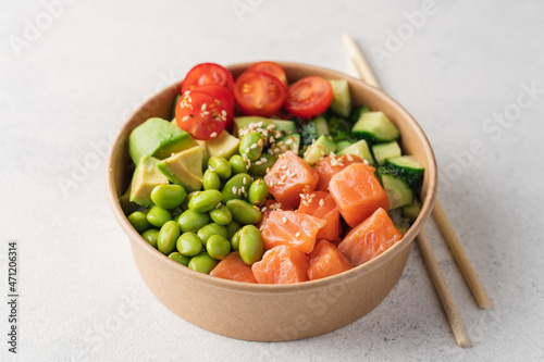 Salmon, avocado, cucumber, tomato, edamame beans and rice poke bowl on light gray background