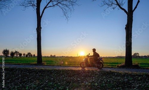Scooter rider on an autumn evening through the polder near Hoogmade. Hoogmade is a village located in the Dutch municipality of Kaag en Braassem in the green heart of the Netherlands