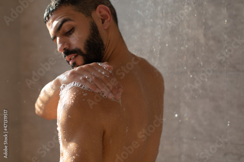 Young man washing his body with soap foam