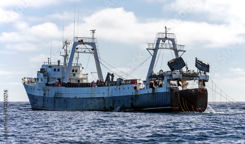 Large fishing trawler is fishing for fish and seafood in the ocean.