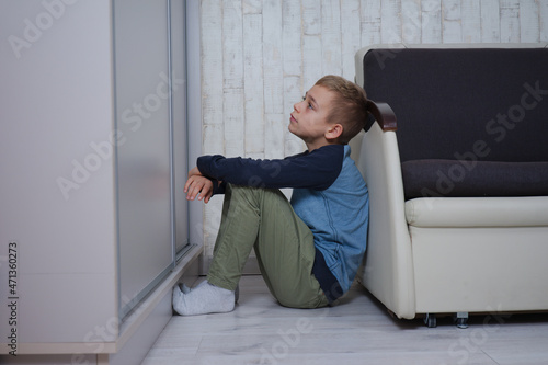 mały chłopak siedzi oparty o fotel, jest smutny