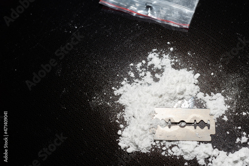 Razor Blade on drug powder,cocaine bag on reflection black background.Copy space.