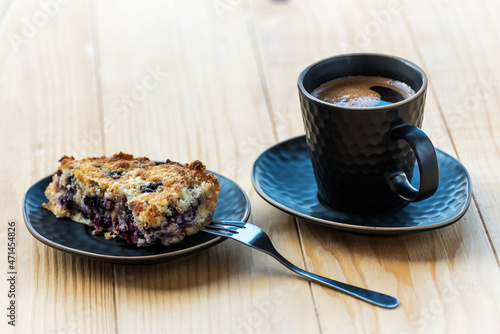 Homemade delicious sliced Apple Blueberry Pie on a black serving plate and a cup of black coffee on a wooden table. Selective Focus