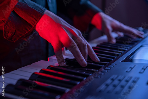 Male hands playing electric Digital Piano. Musician man with black guitar at a rock concert